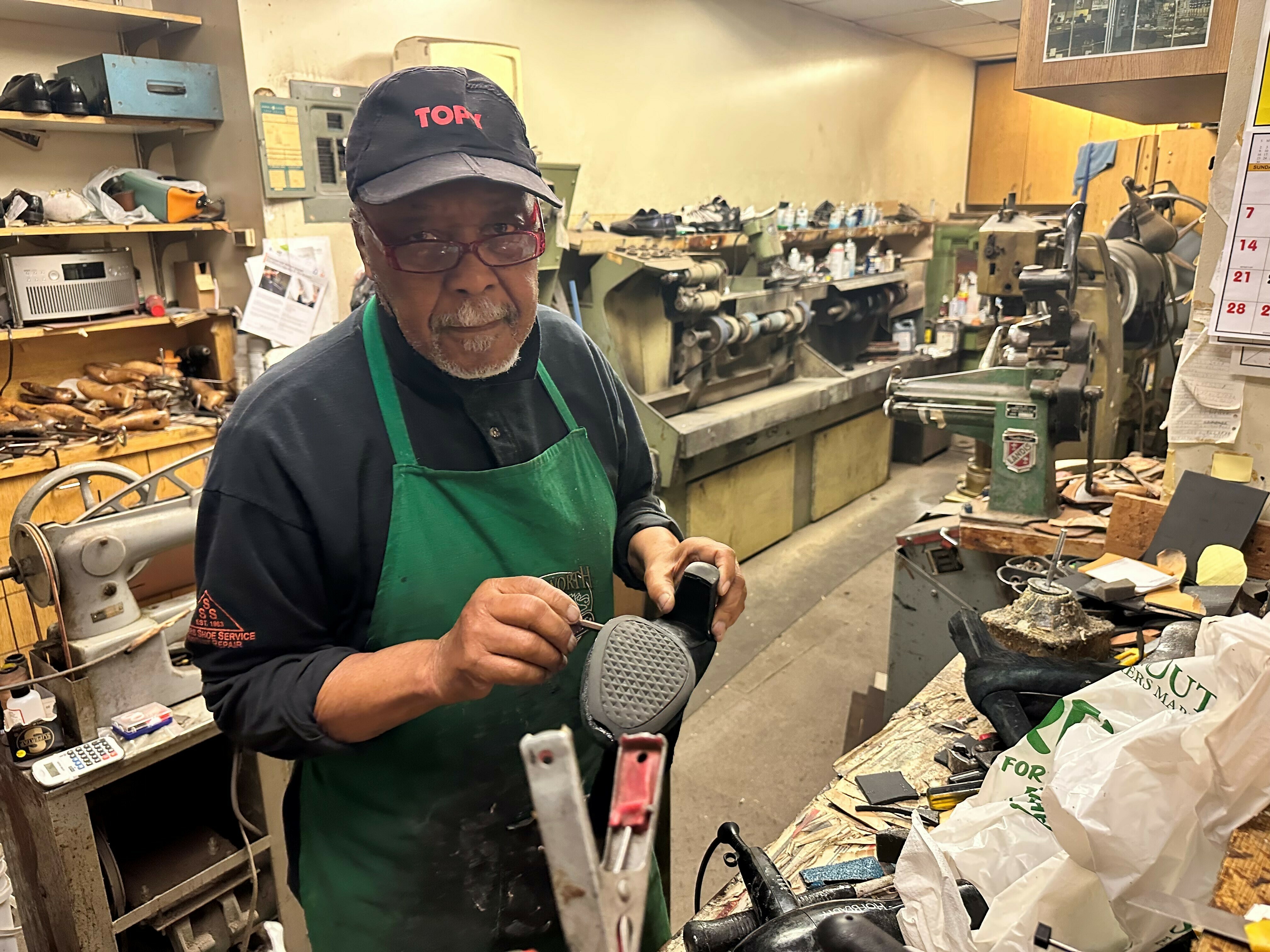 caption: Cobbler James Wallace Sears has spent decades fixing the shoes of lawyers, consultants and financial advisers who work in nearby corporate towers. With so many of them still working from home, he's not sure his business will survive.