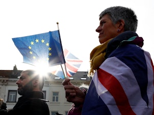 caption: An anti-Brexit demonstrator holds British and European Union flags during a protest in front of the European Parliament in Brussels on Thursday.
