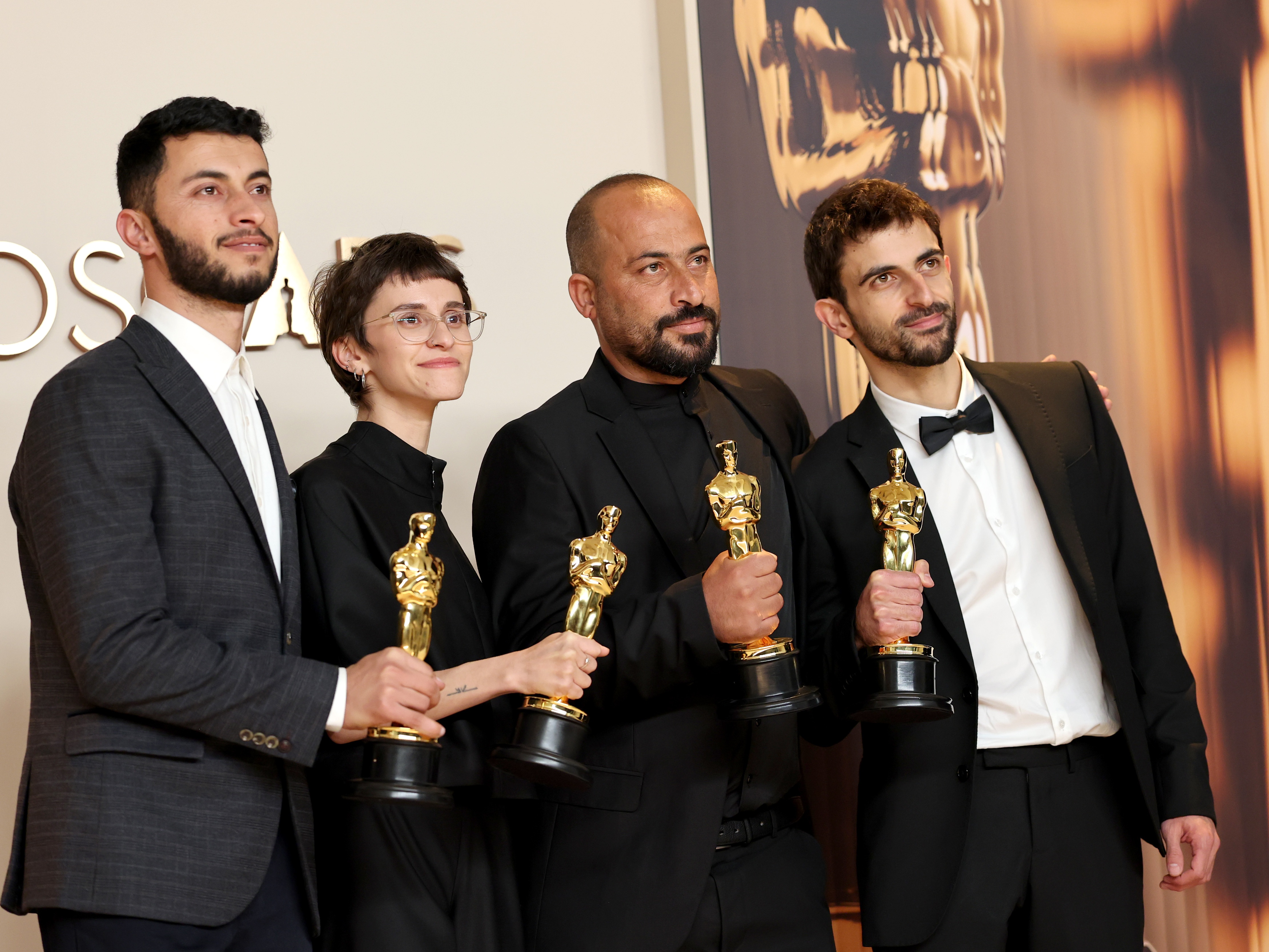 caption: From left: Basel Adra, Rachel Szor, Hamdan Ballal and Yuval Abraham pose with their Oscar awards for best documentary for the film <em>No Other Land</em> in the press room at the 97th Academy Awards in Los Angeles on Sunday.
