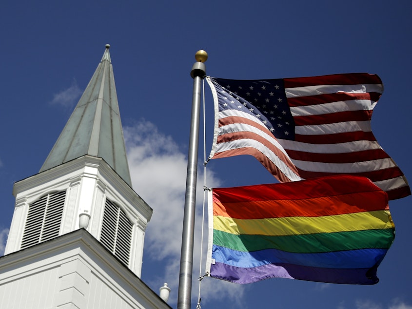 caption: A rainbow flag representing LGBTQ pride flies below the U.S. flag in front of the Asbury United Methodist Church in Prairie Village, Kan., on April 19, 2019.