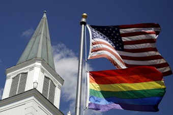 caption: A rainbow flag representing LGBTQ pride flies below the U.S. flag in front of the Asbury United Methodist Church in Prairie Village, Kan., on April 19, 2019.