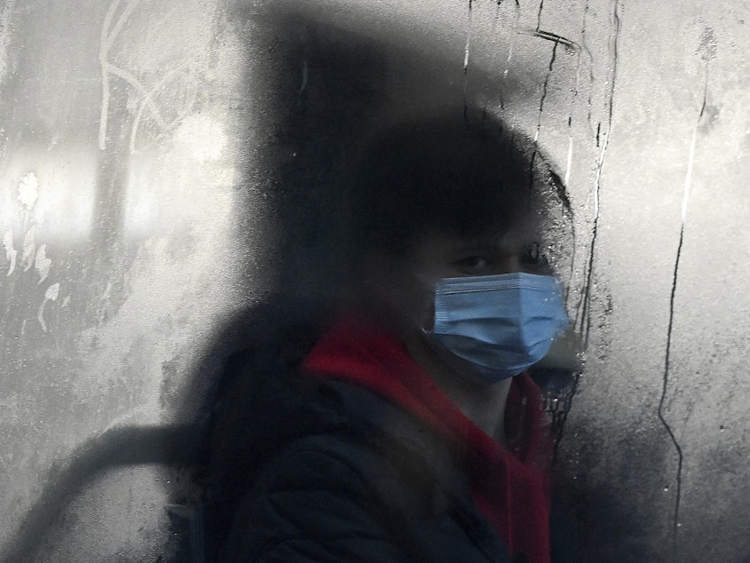 caption: A commuter masks up for a bus ride in Liverpool. The omicron variant has surged in the U.K. — and is now dominant in the U.S. as well. There's now data indicating just how severe the symptoms might be.