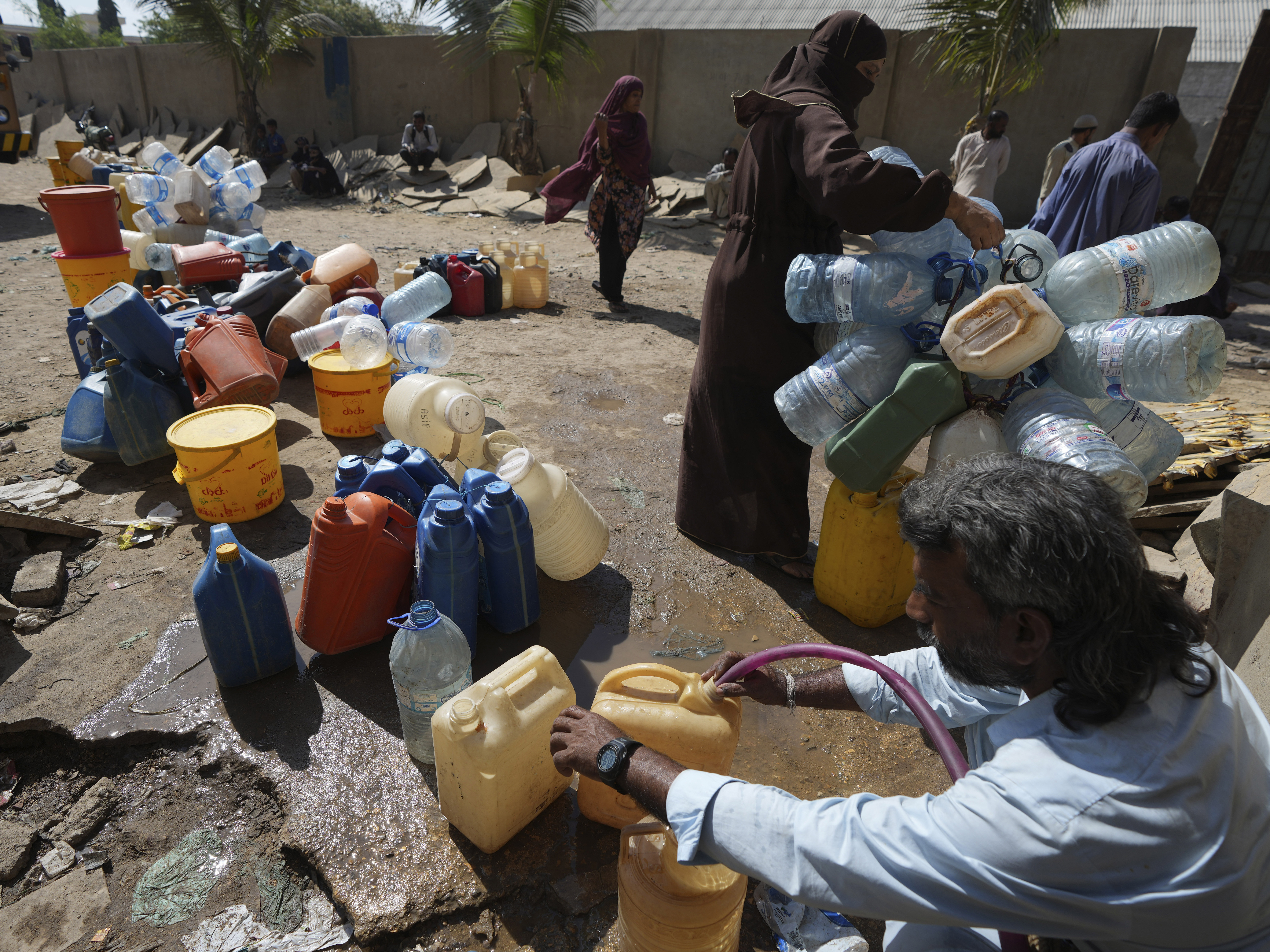 People get drinking water from a water collecting point at a slum area, in Karachi, Pakistan, Tuesday, March 21, 2023. World Water Day will be observed on March 22, to aim to highlight the importance of freshwater and advocate for sustainable management of this vital resource.