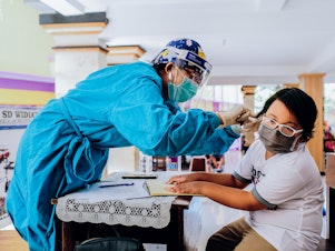 caption: Vaccines for measles-rubella and cervical cancer are administered at a school in Jimbaran, Indonesia. Vaccination rates have dropped during the pandemic.