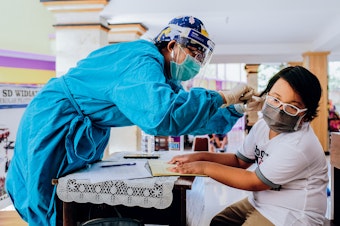 caption: Vaccines for measles-rubella and cervical cancer are administered at a school in Jimbaran, Indonesia. Vaccination rates have dropped during the pandemic.