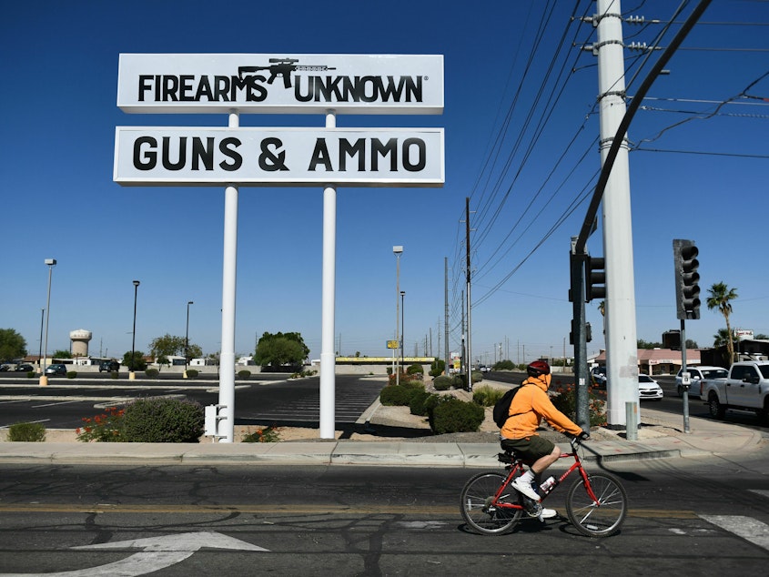 caption: The silhouette AR-15-style rifle is displayed on signage for the Firearms Unknown Guns & Ammo gun store in Yuma, Ariz., last week.