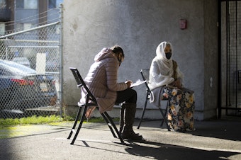caption: Sara Teklesenbet, left, fills out paperwork for her mother, Ghenet Teklu, right, while waiting in line to receive the first dose of the Moderna Covid-19 vaccine on Wednesday, February 3, 2021, at a vaccine clinic set up by the Somali Health Board in partnership with the Othello Station Pharmacy to vaccinate 100 seniors in the community at the Brighton Apartments complex on Rainier Avenue South in Seattle. 