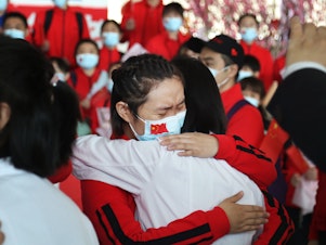 caption: Health workers from Tongji Hospital in Wuhan, China, share an emotional embrace with their peers from a hospital in Jilin province at the Tianhe Airport. Colleagues who worked on the front lines together bid farewell as Wuhan lifted its coronavirus lockdown in April.