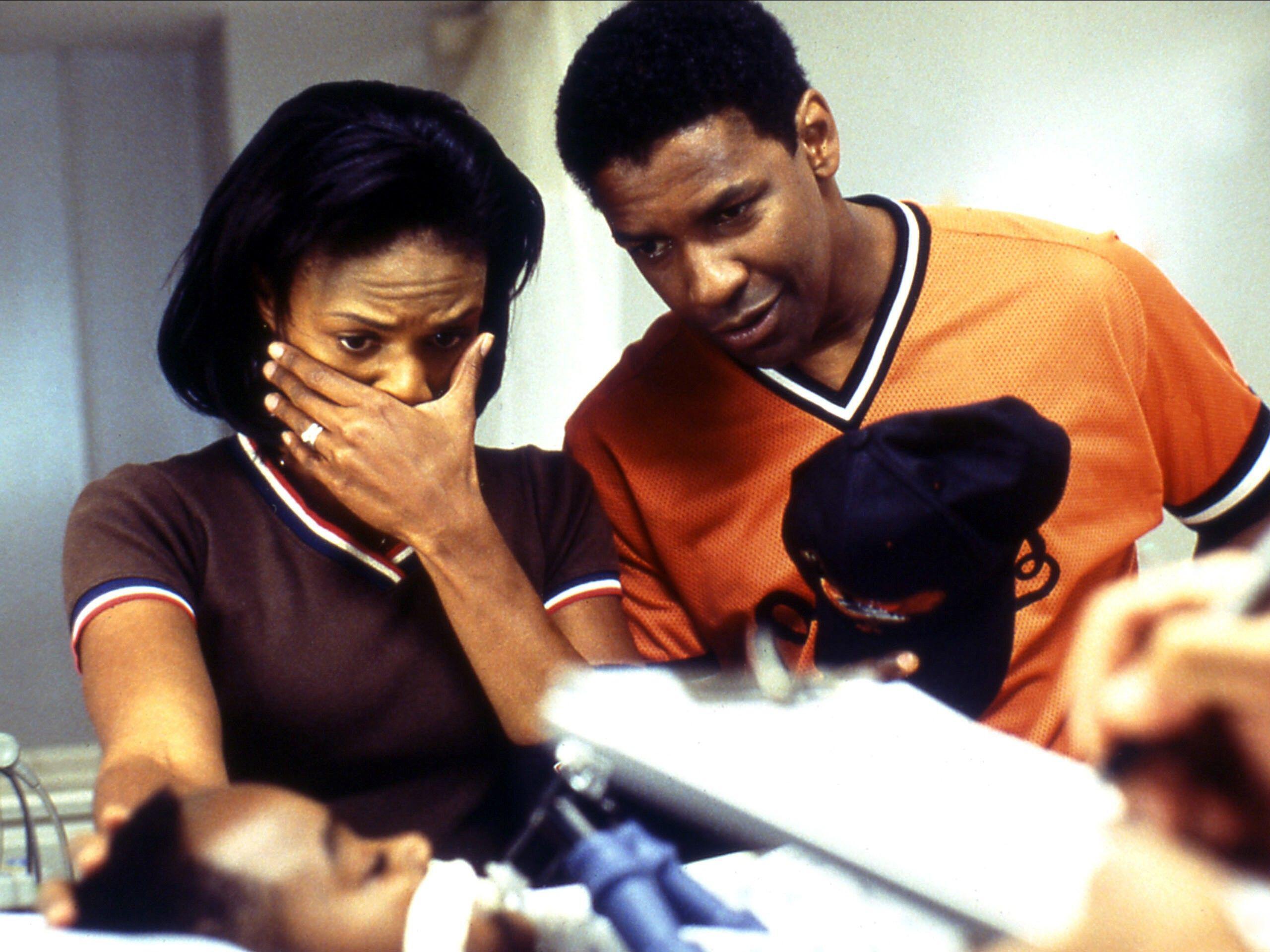 caption: In the 2002 medical thriller <em>John Q, </em>Denzel Washington and Kimberly Elise play parents who learn that their 9-year-old son's heart transplant won't be covered by insurance.