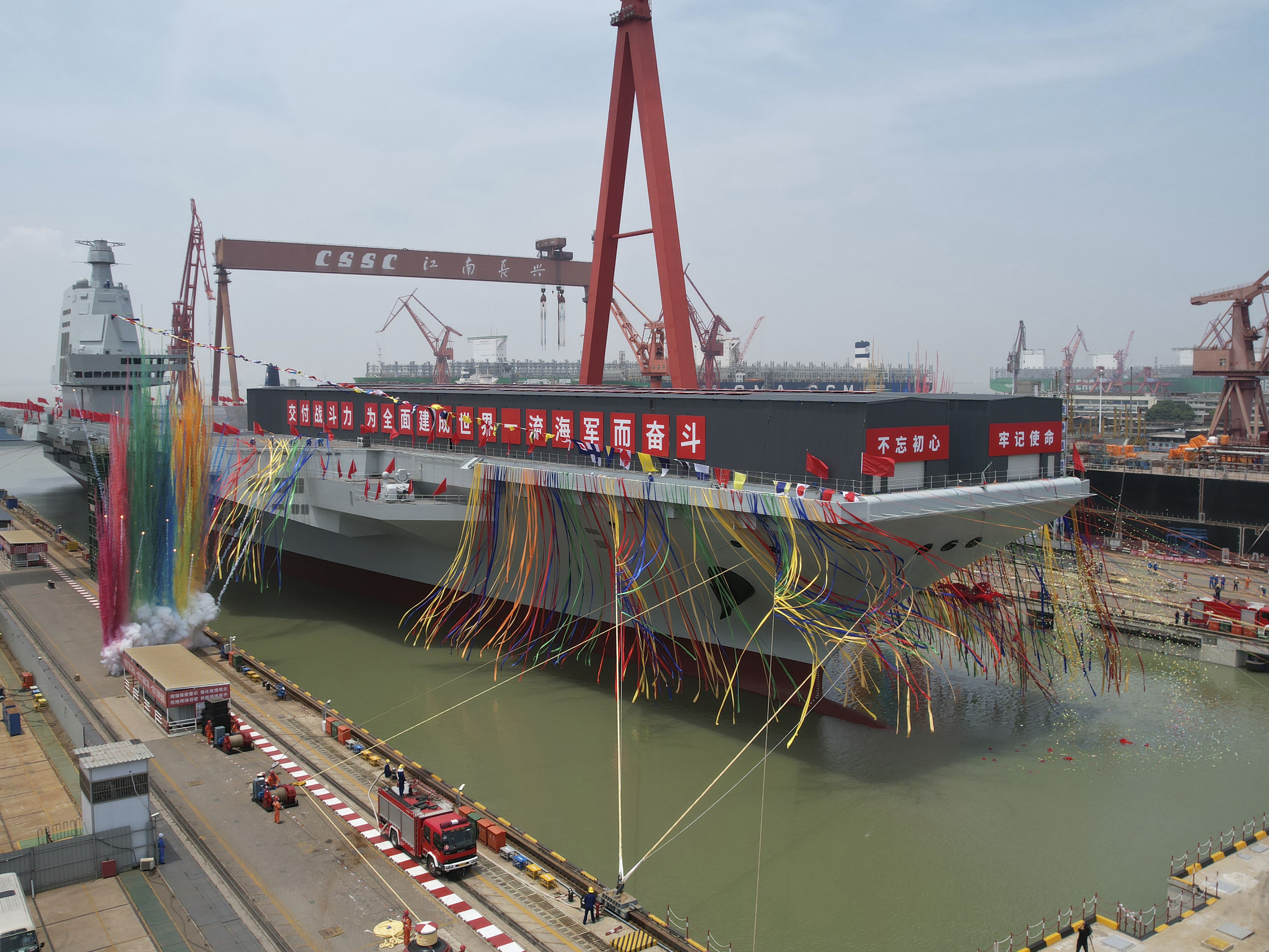 caption: In this photo released by Xinhua News Agency, colored smoke mark the launch ceremony for China's third aircraft carrier christened Fujian at a dry dock in Shanghai on Friday, June 17, 2022.