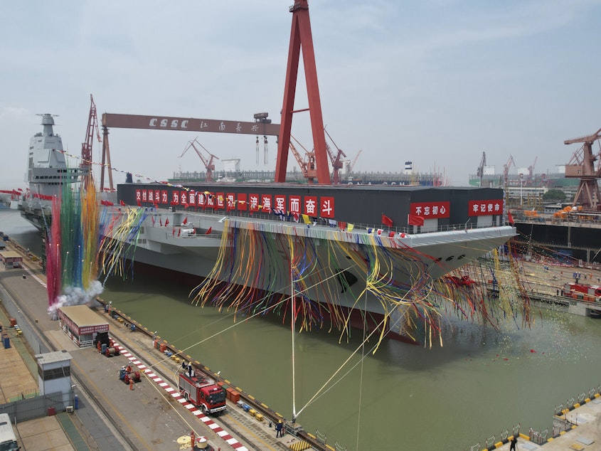 caption: In this photo released by Xinhua News Agency, colored smoke mark the launch ceremony for China's third aircraft carrier christened Fujian at a dry dock in Shanghai on Friday, June 17, 2022.