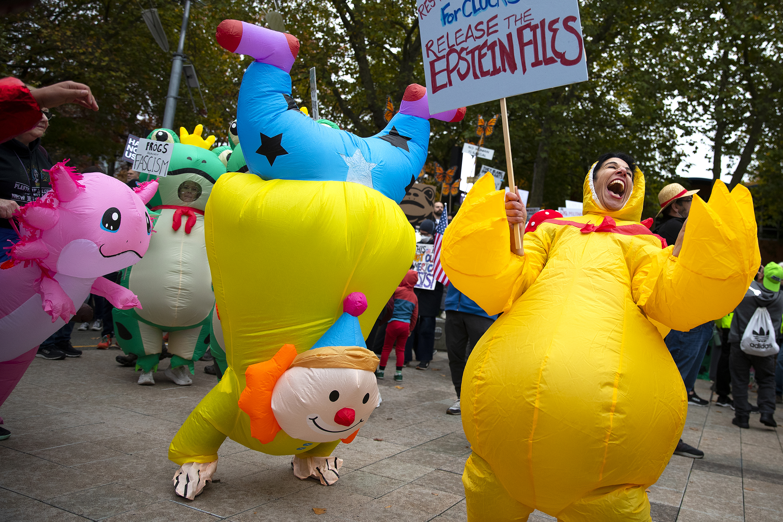 caption: Protesters, including Amina Suchoski, right, dance and laugh while dressed in inflatable costumes during the No Kings rally on Saturday, October 18, 2025, at Seattle Center. 