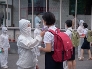 caption: Students of the Pyongyang Jang Chol Gu University of Commerce in North Korea undergo temperature checks before entering the campus. The country said there were no cases — until May 12.