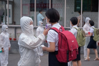 caption: Students of the Pyongyang Jang Chol Gu University of Commerce in North Korea undergo temperature checks before entering the campus. The country said there were no cases — until May 12.