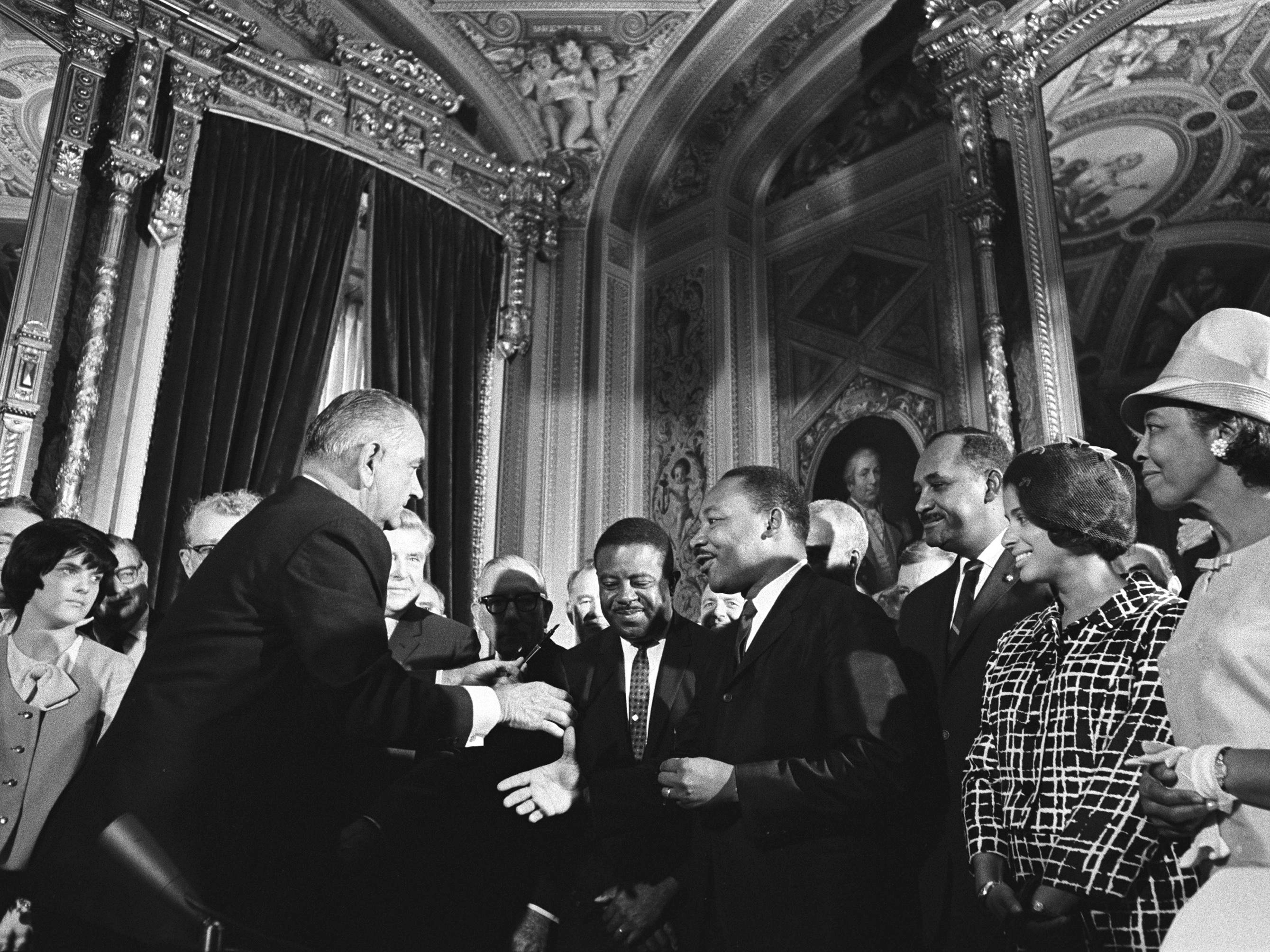caption: President Lyndon B. Johnson moves to shake hands with Martin Luther King Jr. while others look on after Johnson signed the federal Voting Rights Act into law at the U.S. Capitol in Washington, D.C., on Aug. 6, 1965.