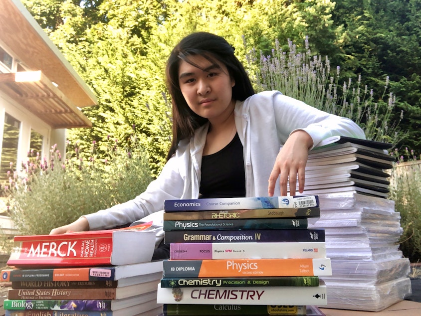 caption: The school records that Lisa Chua kept (saran-wrapped, bottom of right stack) got Emily Chua into college. Also pictured are some of the textbooks and notebooks that got Emily through high school.