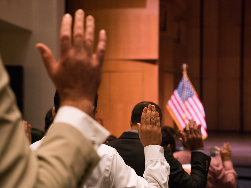 caption: Newly sworn-in U.S. citizens gather for a naturalization ceremony at the Rachel M. Schlesinger Concert Hall and Arts Center in Alexandria, Va., in August. The Trump administration is planning to include a question about U.S. citizenship status on the 2020 census.