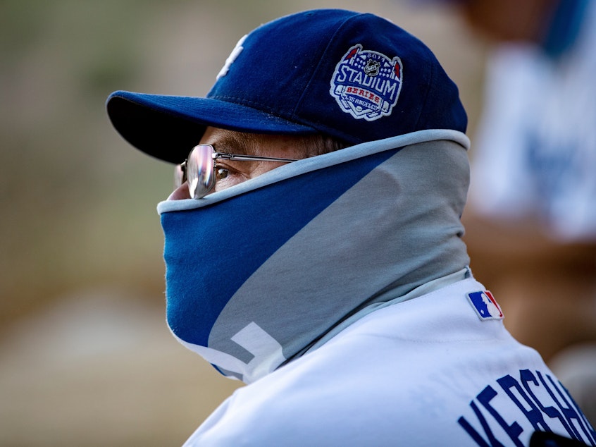 caption: A fan wears a neck gaiter as he watches the L.A. Dodgers play the San Francisco Giants in Los Angeles.