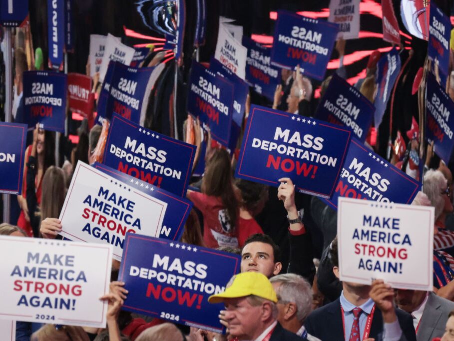 caption: Attendees at the Republican National Convention hold up signs reading "Mass Deportation Now!" last month in Milwaukee.