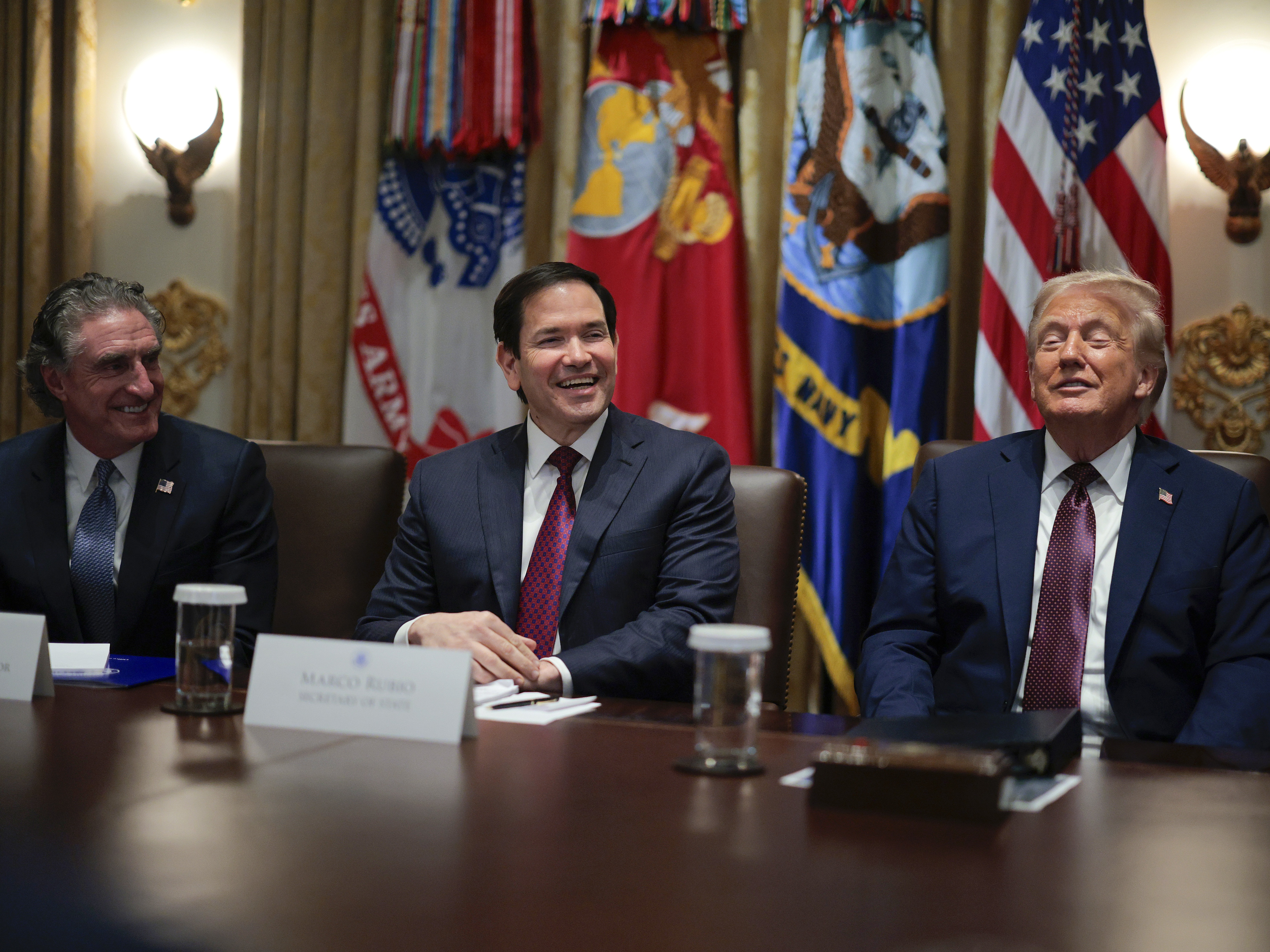 caption: U.S. Secretary of the Interior Doug Burgum, Secretary of State Marco Rubio and President Trump sit together during a Cabinet meeting in the Cabinet Room of the White House on Aug. 26. Rubio is among a number of officials to have multiple jobs in the administration.