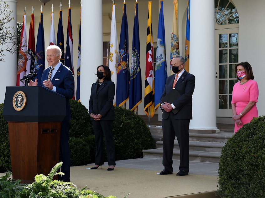 caption: President Biden, with (L-R) Vice President Kamala Harris, Senate Majority Leader Chuck Schumer, and House Speaker Nancy Pelosi, Democrat of California, speaks about the American Rescue Plan in the Rose Garden of the White House on Friday.