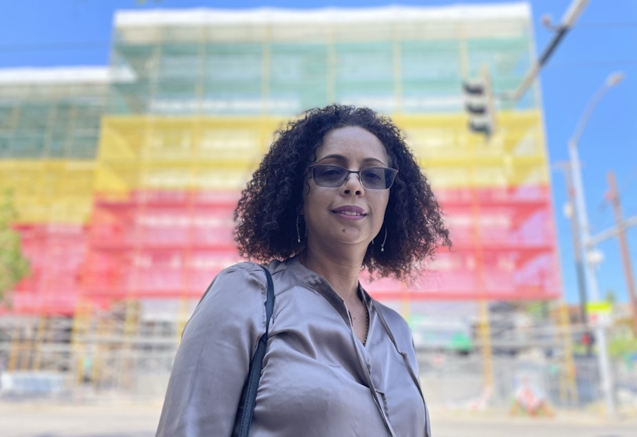 caption: Sophia Benalfew, director of the group Ethiopian Communities of Seattle, stands in front of the almost complete Ethiopian Village project in summer of 2022