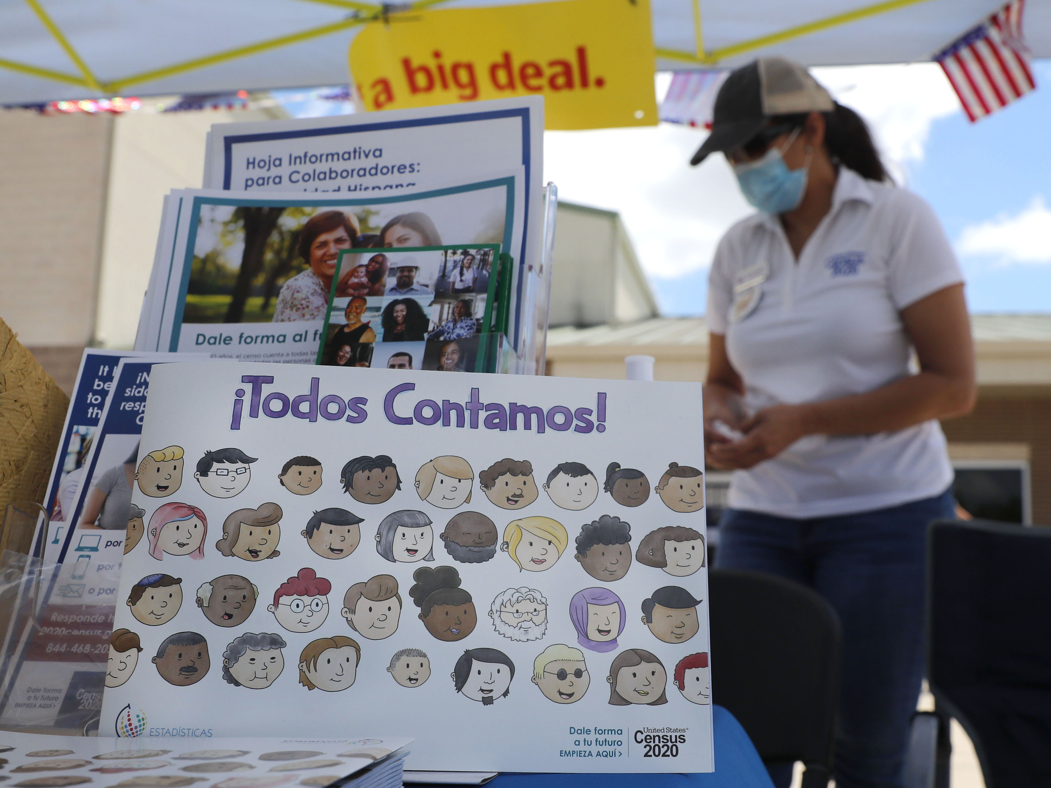 caption: U.S. Census Bureau worker Marisela Gonzales stands by a display of books and flyers about the 2020 census at a walk-up counting site in Greenville, Texas, in July. The bureau's employees are under a time crunch to try to complete the national head count after the agency announced that counting will end a month early.