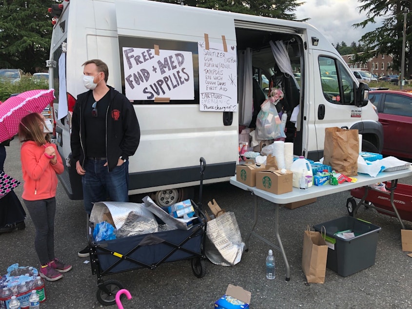 caption: At Magnuson Park in Seattle, volunteers offer supplies protesters, including medical supplies. Many protestors wore plastic goggles, anticipating tear gas from police. That didn't happen at this Seattle protest, but it did happen at other protests in the city on the same night.