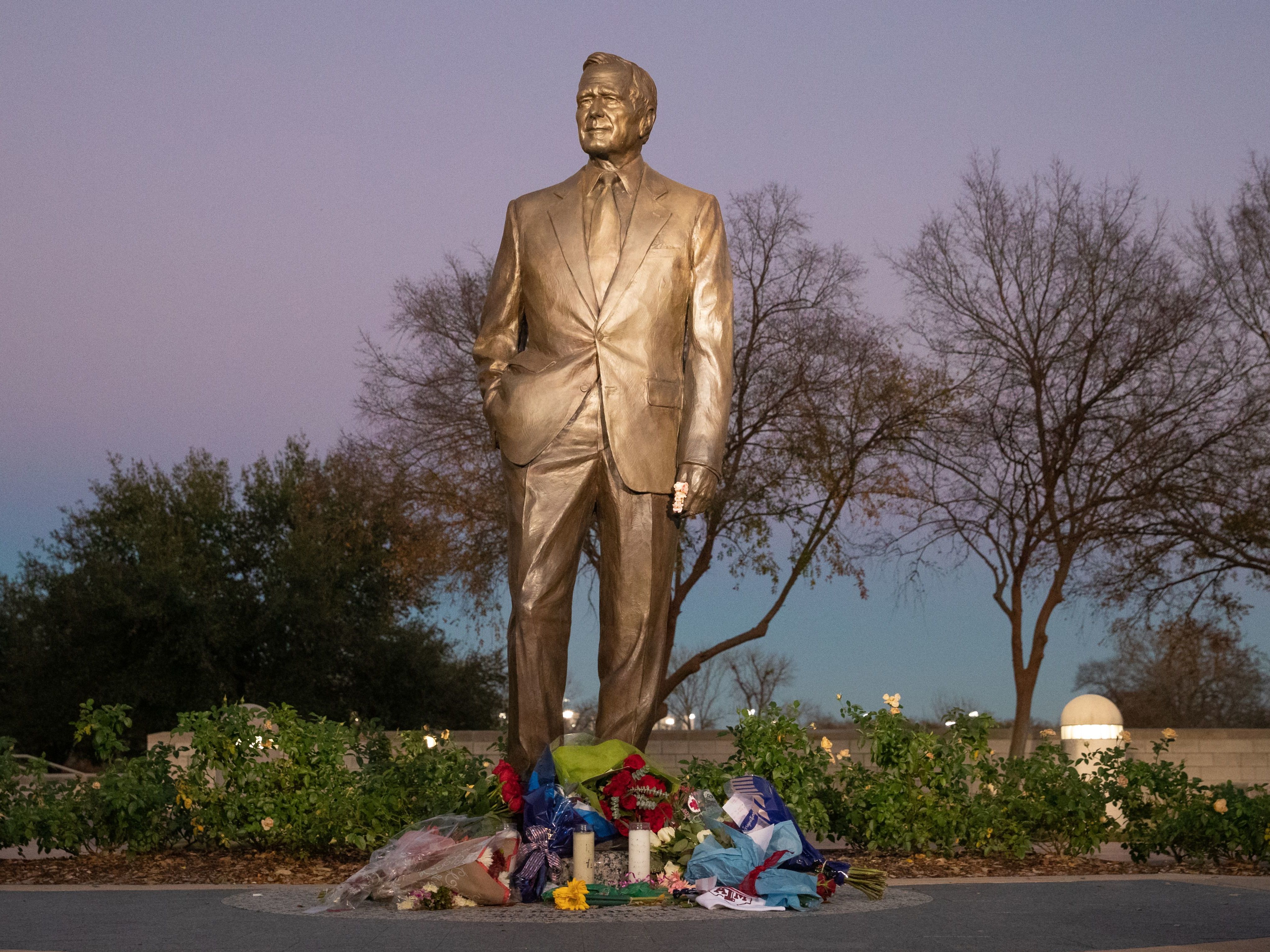 caption: Flowers laid are seen at the base of the statue at the George Bush Presidential Library in College Station, Texas on December 1, 2018.