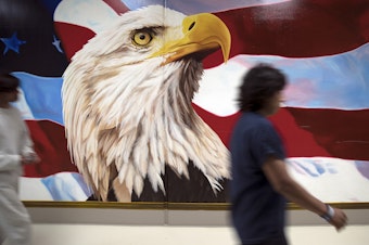 caption: Dozens of murals hang on the walls at the Northwest Detention Center. They're painted by detainees.