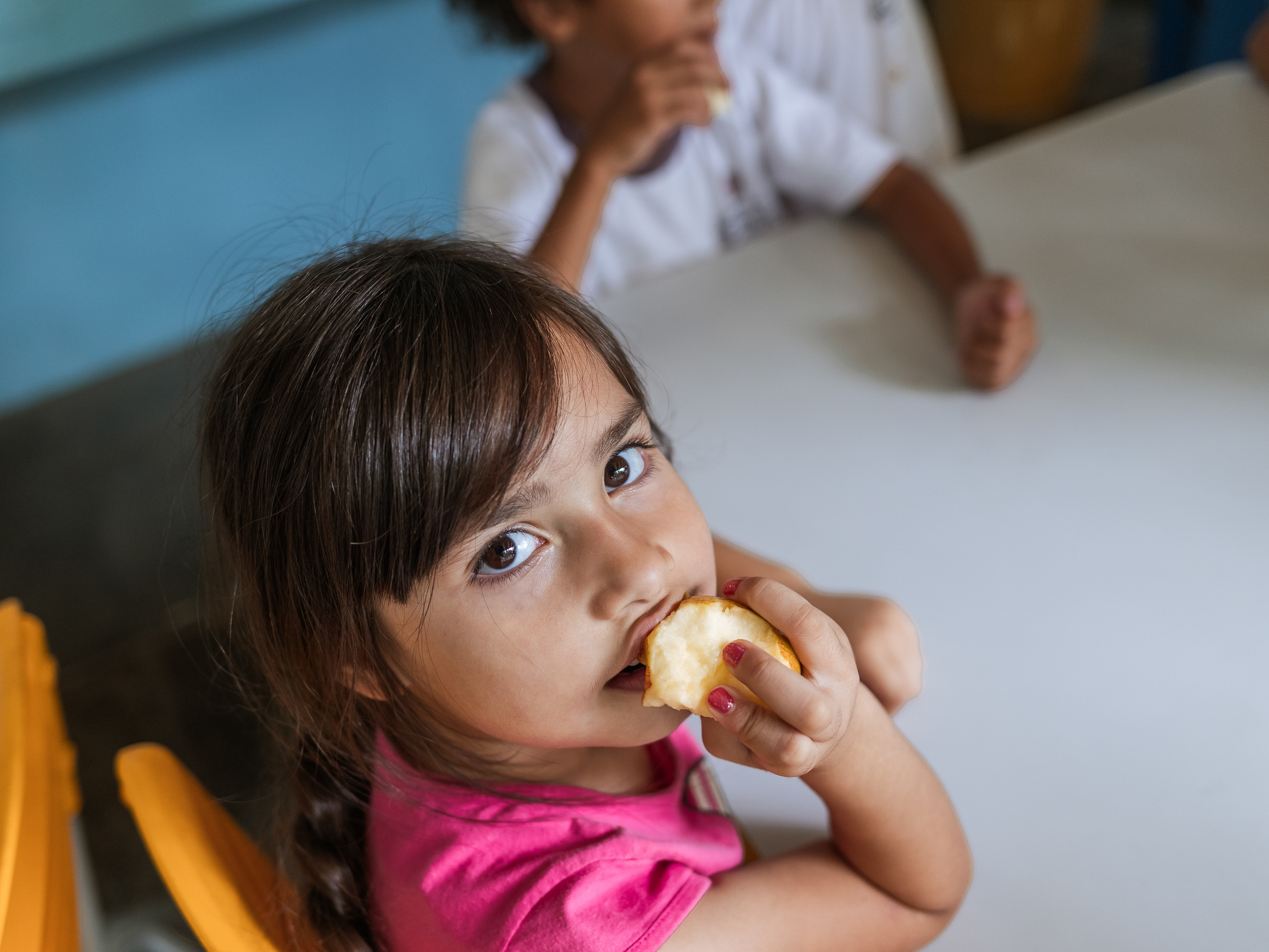 caption: A student at Professor Lourdes Heredia Mello Municipal School in São Paulo enjoys an apple for dessert after lunch. Brazil's school lunch program, enshrined in its constitution, is a pillar of the country's anti-poverty efforts.