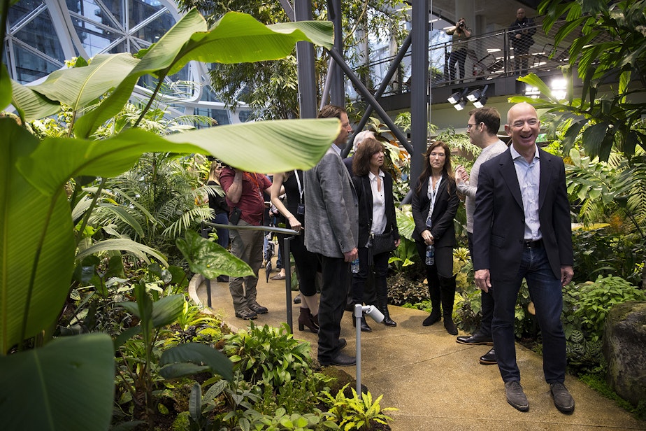 caption: Amazon CEO Jeff Bezos tours the Amazon Spheres greenhouse in 2018. His company plans to disclose its contribution to the greenhouse effect in 2019.