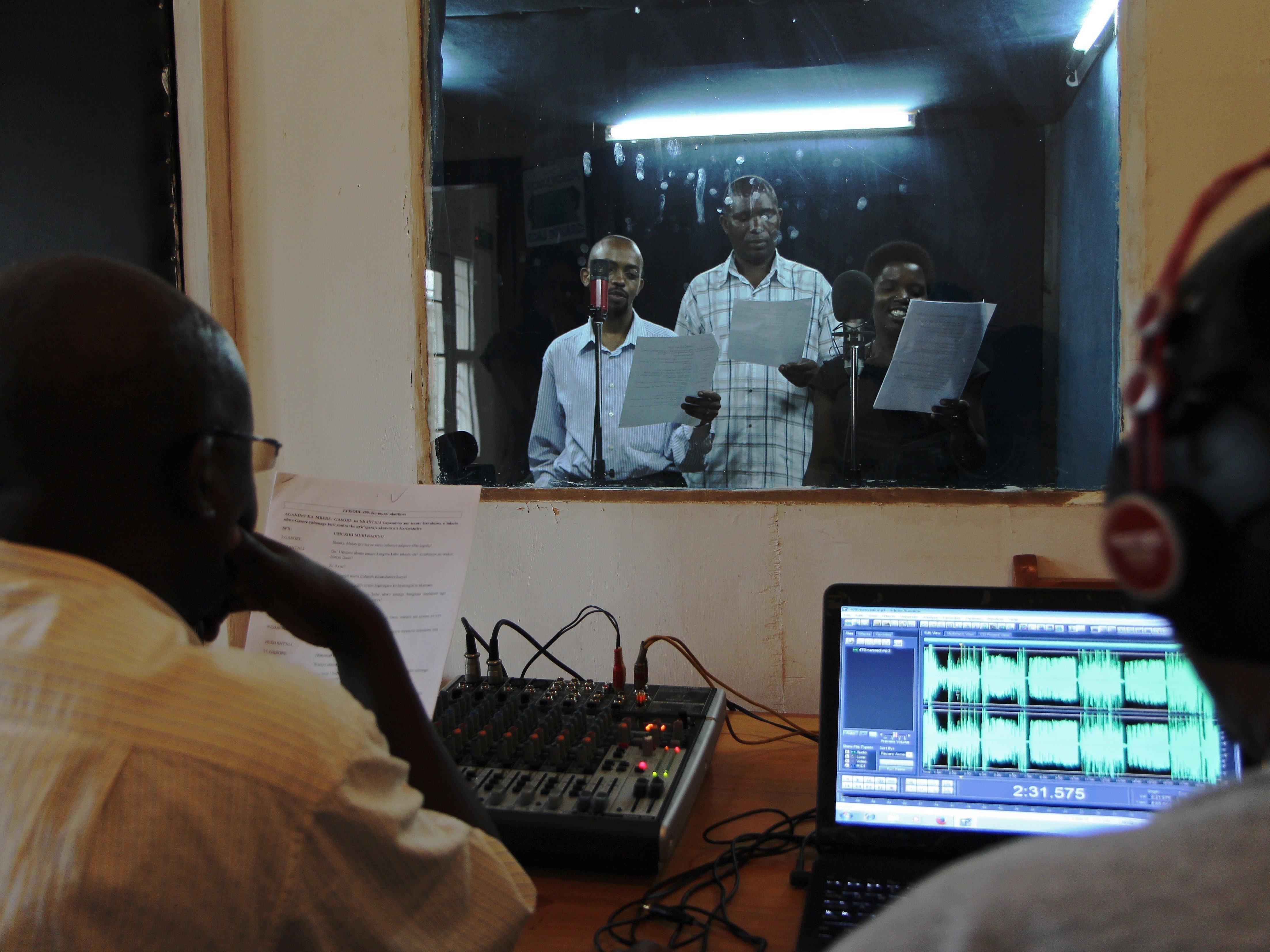 caption: Actors reading during the recording of an episode of the radio soap opera "Musekeweya" in Kigali, produced by the NGO <a href="http://www.labenevolencija.org/">Radio La Benevolencija.</a> Twice a week, people all around Rwanda gather in groups to listen together.