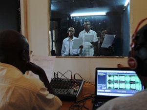caption: Actors reading during the recording of an episode of the radio soap opera "Musekeweya" in Kigali, produced by the NGO <a href="http://www.labenevolencija.org/">Radio La Benevolencija.</a> Twice a week, people all around Rwanda gather in groups to listen together.