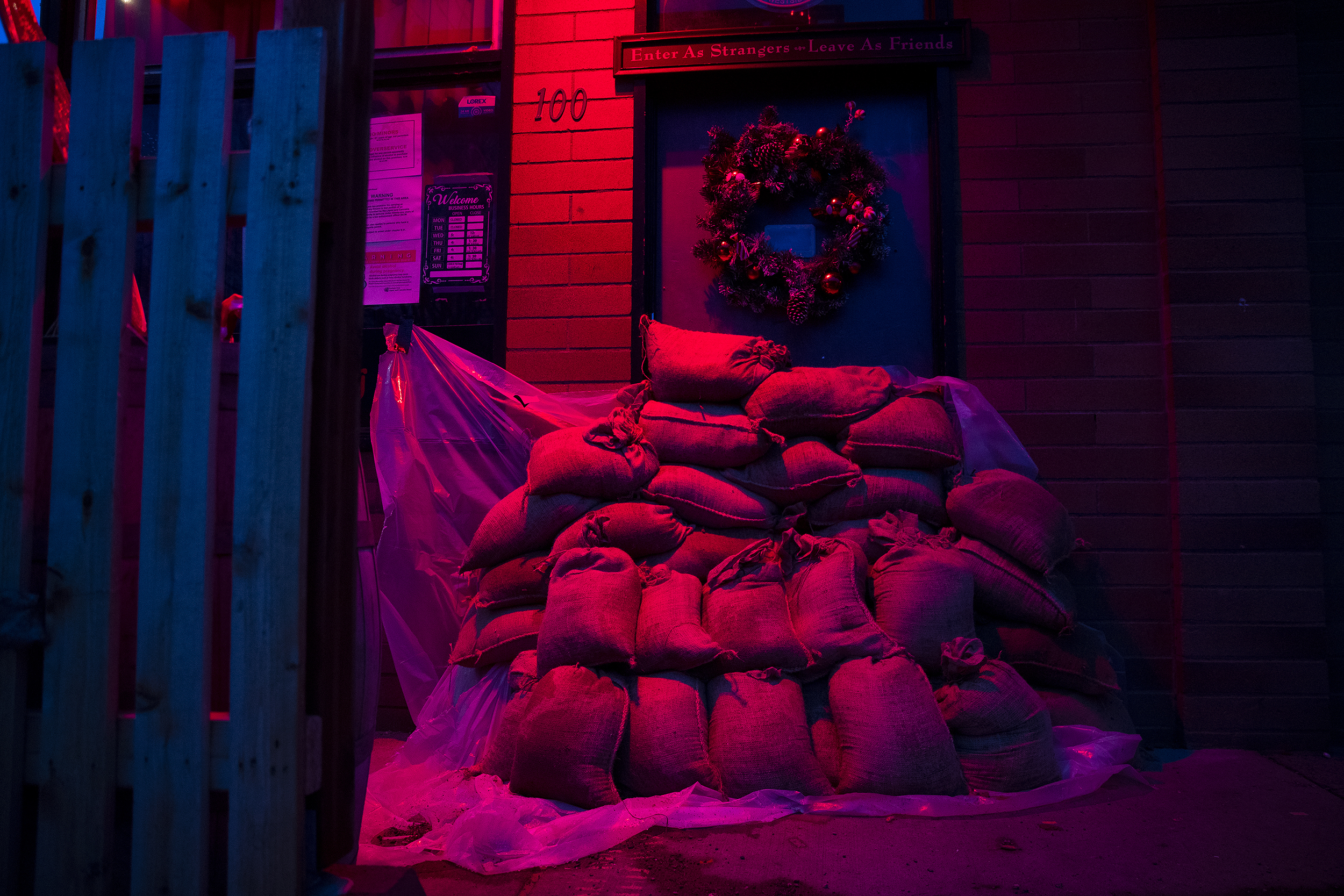 caption: Sand bags barricade the entrance to Katt’s Westside Stories bar along South Barker Street early in the morning on Thursday, December 11, 2025, in Mount Vernon. 100,000 people in Western Washington have been advised to evacuate from their homes.