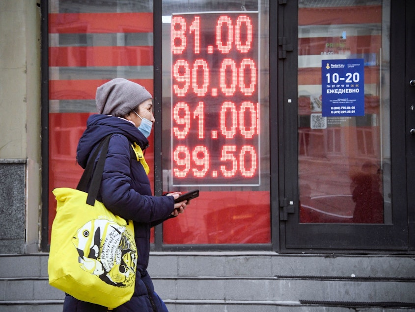 caption: A woman walks past a currency exchange office in central Moscow on February 24, 2022.