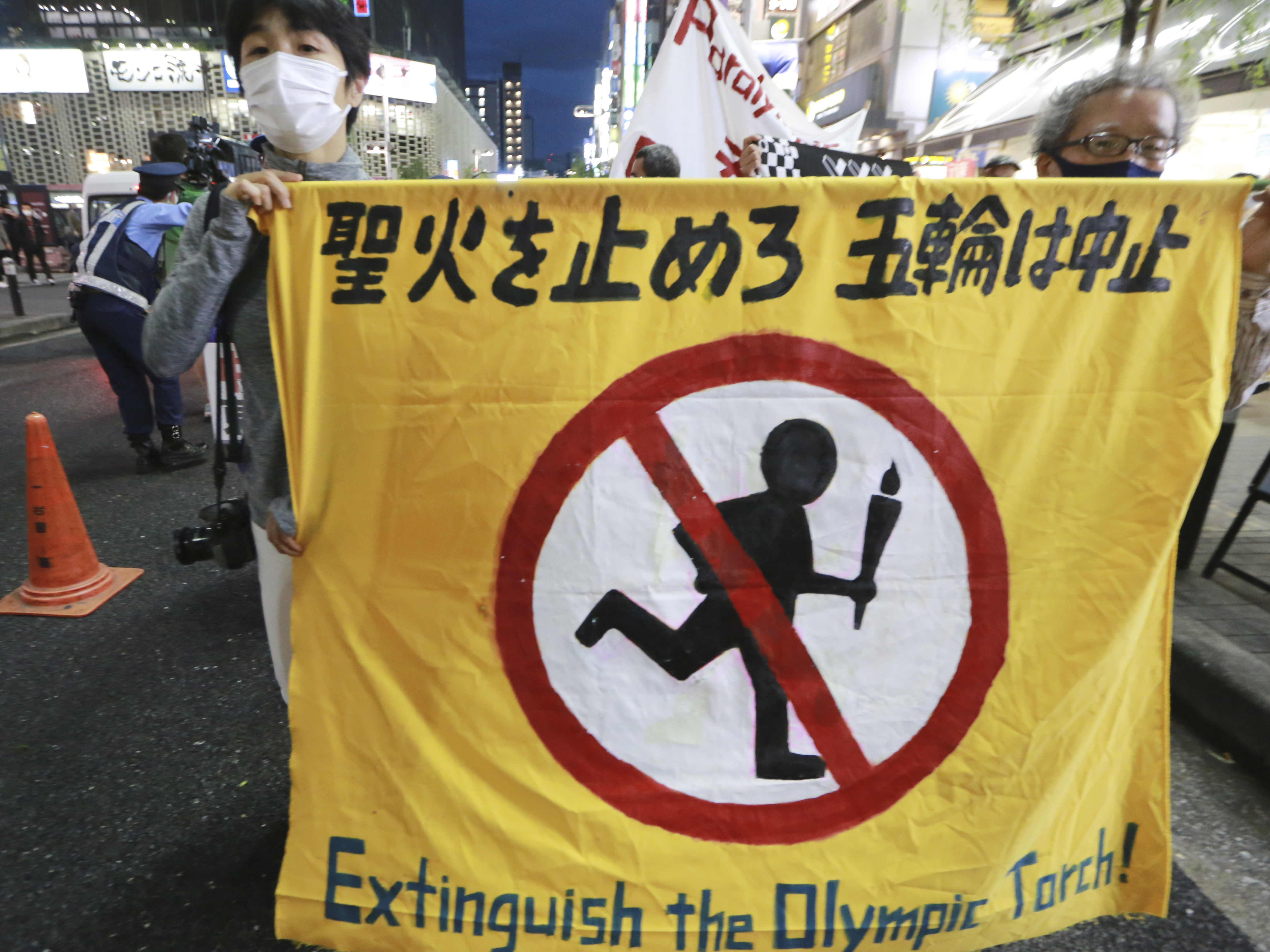 caption: People carry a banner reading "Extinguish the Olympic torch" during a march in Tokyo last week calling for the cancellation of the Summer Olympics. The government insists the games will go on despite concerns about the coronavirus.