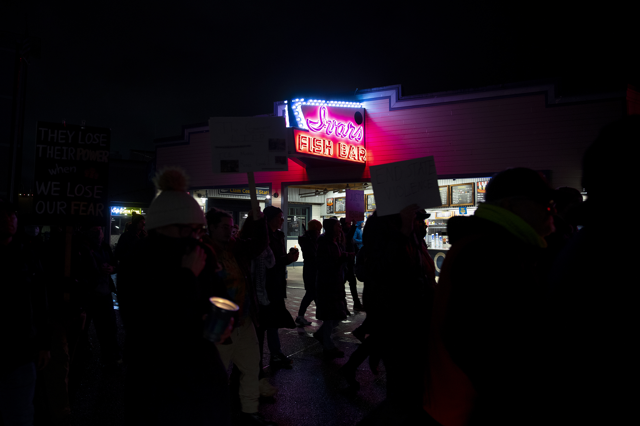 caption: Hundreds march along the waterfront following a vigil honoring Renee Nicole Good on Thursday, January 8, 2026, at Pier 58 in Seattle. 