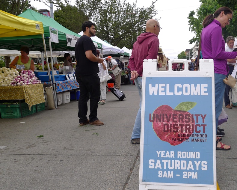 caption: Shoppers peruse produce at the University District farmers market.