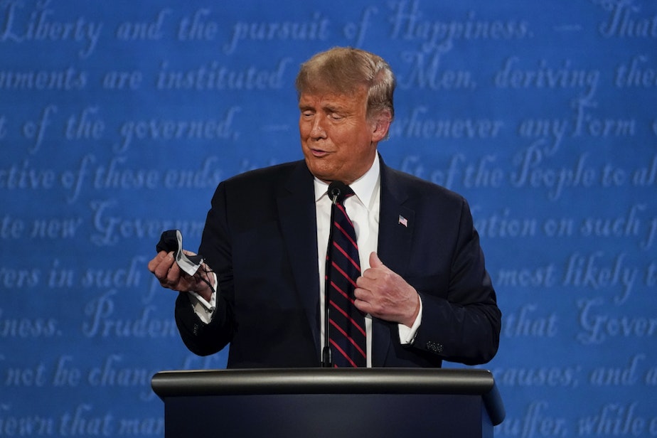 caption: President Donald Trump looks at his facemask during the first presidential debate at Case Western University and Cleveland Clinic, in Cleveland, Ohio. (Julio Cortez/AP Photo)