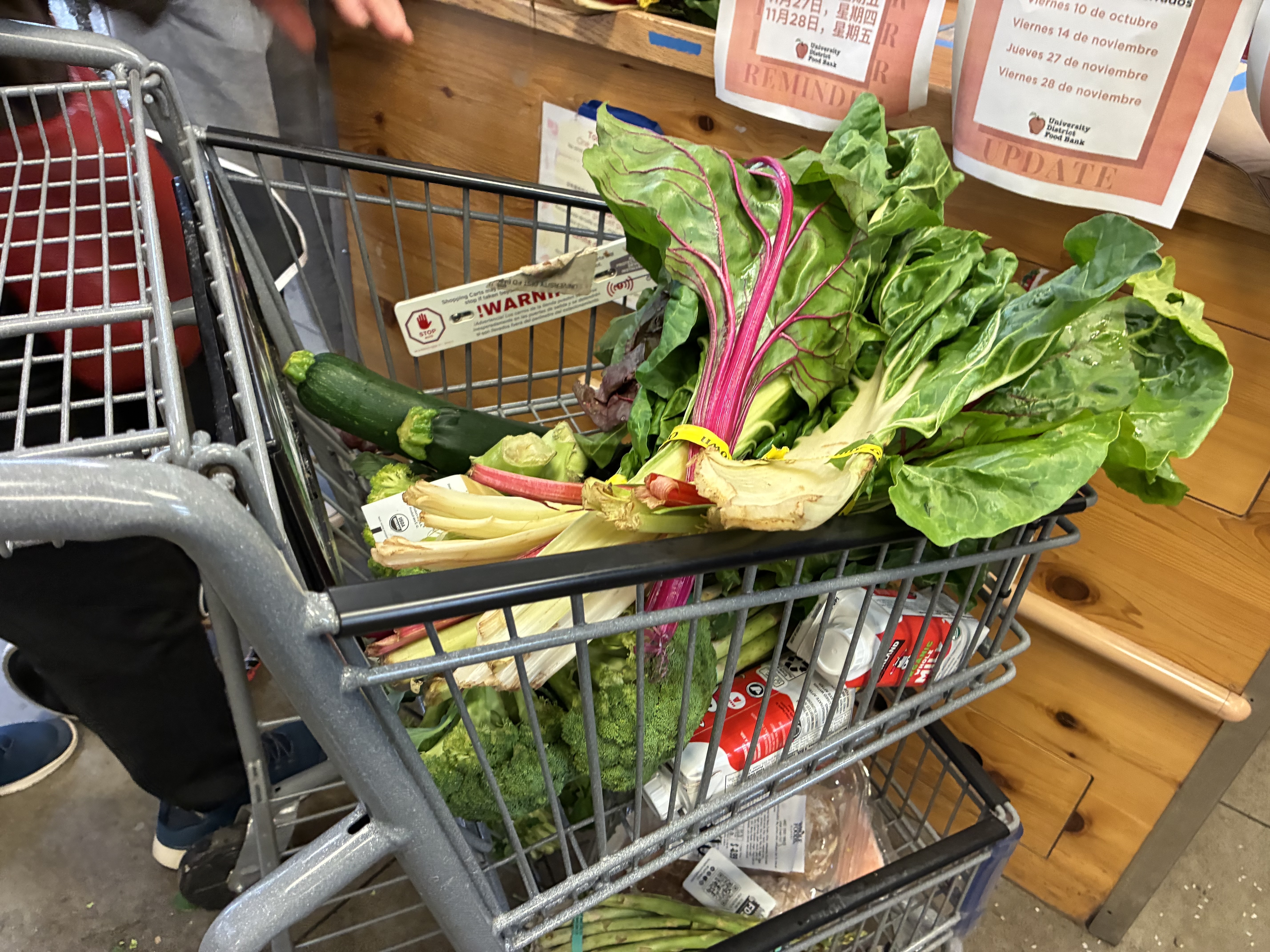 caption: A customer at the University District Food Bank unloads their cart for checkout. 