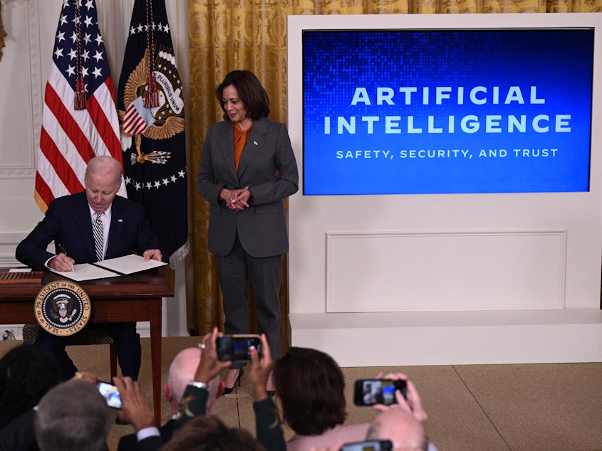 caption: Vice President Harris watches as President Biden signs an executive order on artificial intelligence on Oct. 30. On Thursday, the Biden administration issued new rules on how government agencies can implement AI.