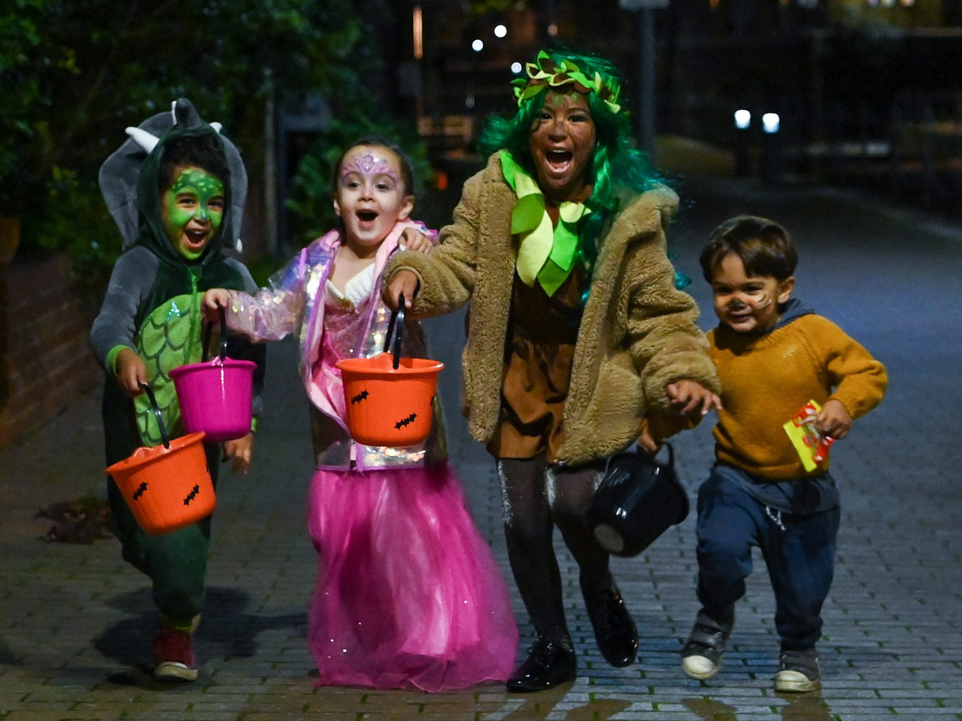 caption: Halloween lets children bring fantasy play into the real world, all while building a sense of community. Here, kids go trick-or-treating during Halloween in  London in 2020.