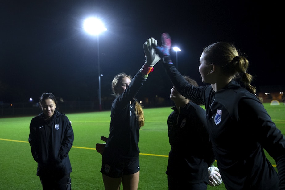 caption: Kylee Bengston, 16, left, high-fives Tyler Roberts, 15, right, during goal keeper training with Seattle Reign Academy on Monday, January 29, 2024, at North SeaTac Park. 