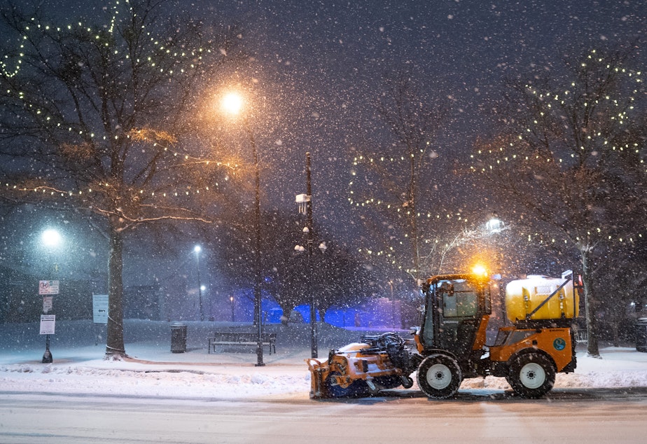 caption: A snow plow clears Main St. on January 16, 2022 in Greenville, South Carolina. Snow, sleet and freezing rain are expected in the area for the remainder of the day.