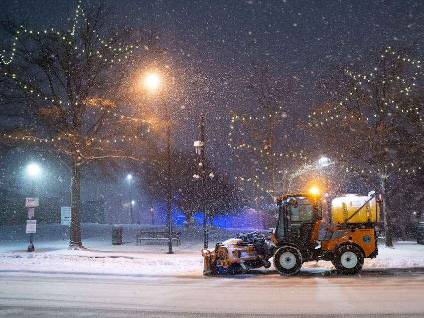 caption: A snow plow clears Main St. on January 16, 2022 in Greenville, South Carolina. Snow, sleet and freezing rain are expected in the area for the remainder of the day.