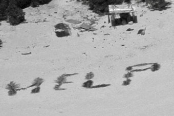 caption: The 'HELP' sign made from palm fronds is shown on the Pikelot atoll.