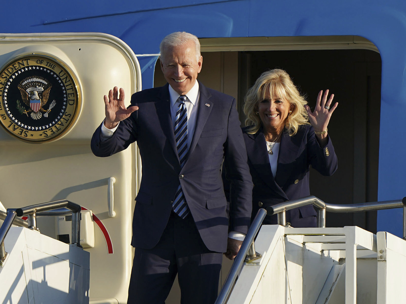 caption: President Joe Biden and First Lady Jill Biden wave as they arrive in England ahead of the G7 summit on Wednesday.