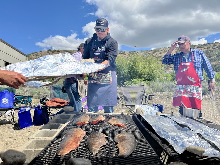 caption: Paul Myrick helps cover salmon filets in foil. While not the traditional way to cook salmon, it helps the fish cook faster.