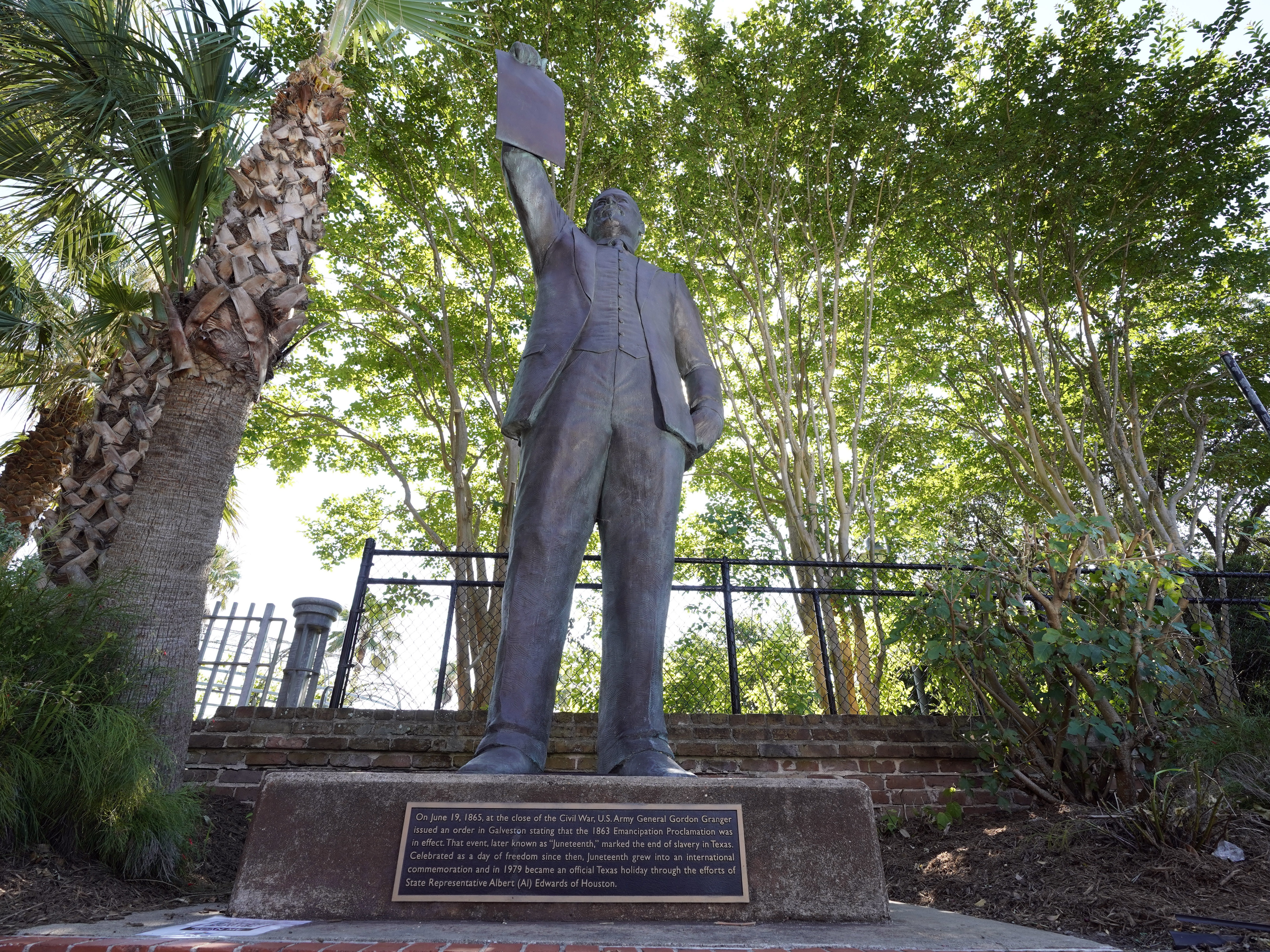 caption: In this June 17, 2020, photo, a statue depicts a man holding the state law that made Juneteenth a state holiday in Galveston, Texas. 